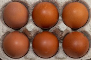 Six dark-chocolate-colored eggs in a carton.