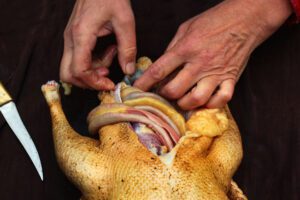 A person removes the innards from a goose.